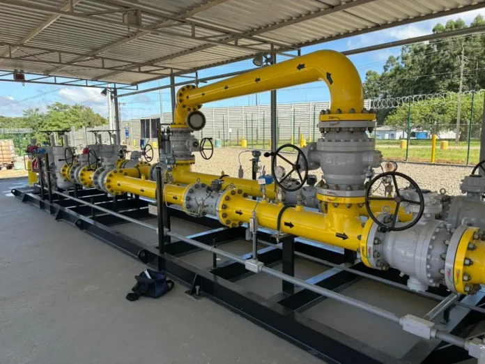 Sistema de tubulação com válvulas e conexões, pintado em amarelo e cinza, sob uma cobertura.