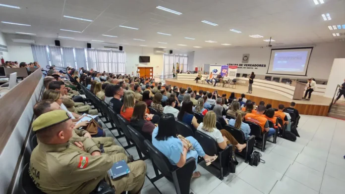 Auditório lotado durante um evento na Câmara de Vereadores, com autoridades e participantes sentados em cadeiras.