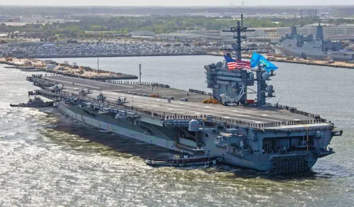 Porta-aviões em movimento na água, com helipontos ocupados e bandeiras visíveis no convés.